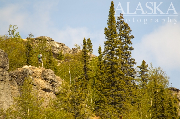 A hiker looks out from on top the rocks.