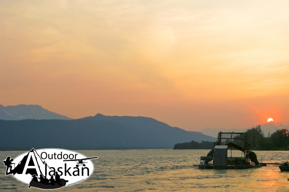 A fish counter scoops fish while the sun sets up the Chilkat River.