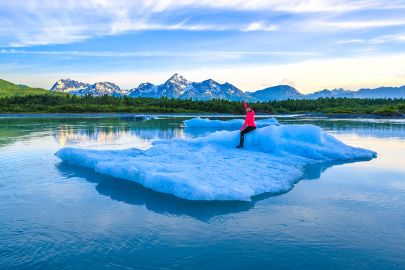 A woman rides an iceberg on our Valdez Glacier and Iceberg tour.