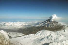 Redoubt Volcano viewed from the northwest following the April 4, 2009 eruption (Event 19). Steam rises from the summit crater, pyroclastic flow and surge deposits drape the flanks, and lahar deposits cover the Drift River Valley.  R. G. McGimsey, USGS, Alaska Volcano Observatory. Public domain